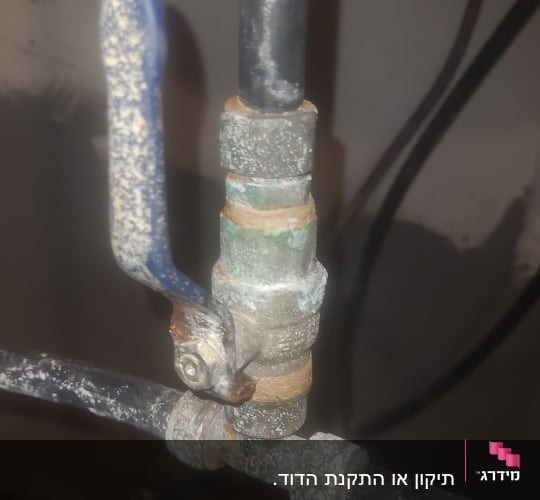 שסתום מתכת עם ידית כחולה, צינורות מחוברים